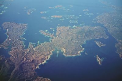 Aerial view of sea and mountains against blue sky