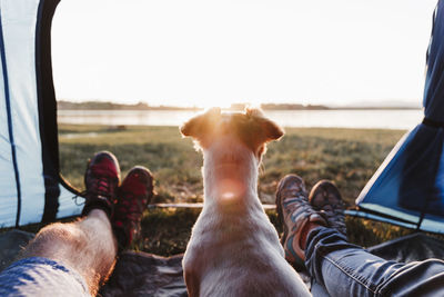 Low section of people relaxing on land against sky