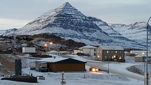 Snow covered houses by mountains against sky at night