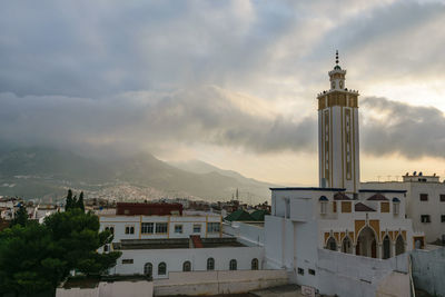 View of lighthouse in city against cloudy sky