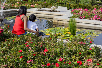 Mother and son from behind looking at the water in a park.