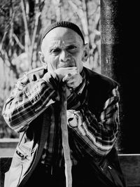 Portrait of senior man sitting against trees