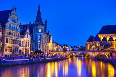 Illuminated buildings against blue sky at night