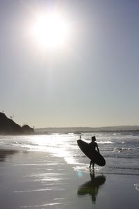 Silhouette man on beach against sky during sunset