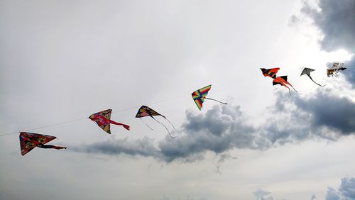 Low angle view of kites flying against sky