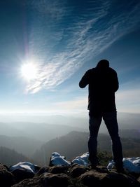 Rear view of man standing on mountain against sky