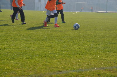 Low section of people playing soccer on field