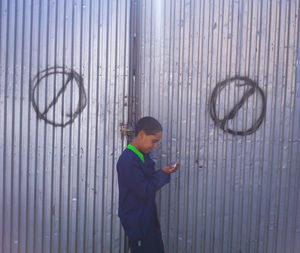 Full length of boy standing against wall