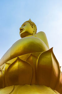 Low angle view of yellow statue against sky