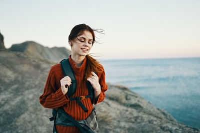 Young woman standing by sea against sky