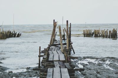 Wooden posts on beach against clear sky