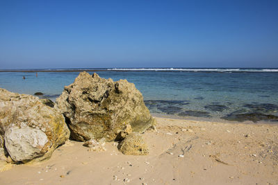 Rocks on beach against clear blue sky