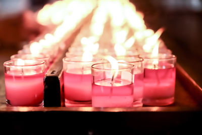 Close-up of lit tea light candles on table in temple