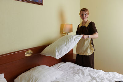 Young woman sitting on bed at home