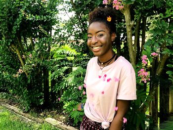 Portrait of smiling young woman standing against plants