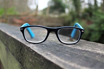 Close-up of eyeglasses on wooden railing