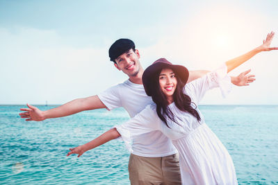 Full length of smiling young couple in sea against sky
