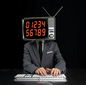 Low angle view of clock on table against black background