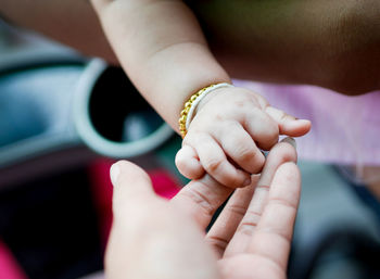 Close-up of person holding baby hand