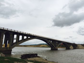 Arch bridge over river against sky