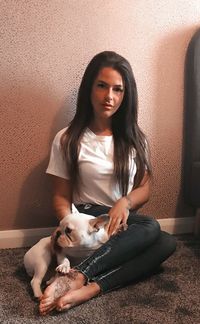 Portrait of young woman with dog sitting at home