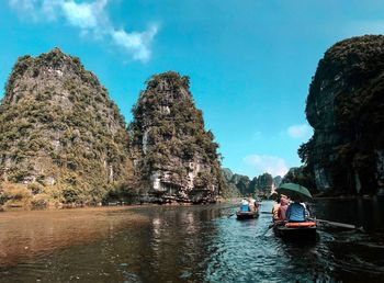 People on rocks by sea against sky