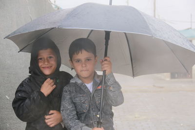 Little refugee children with umbrella in the rain, refugee with umbrella.