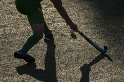 Low section of person playing hockey on road