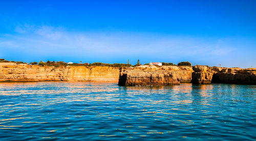 Scenic view of sea against and cliffs against blue sky