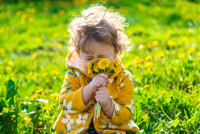 Side view of girl blowing flowers on field