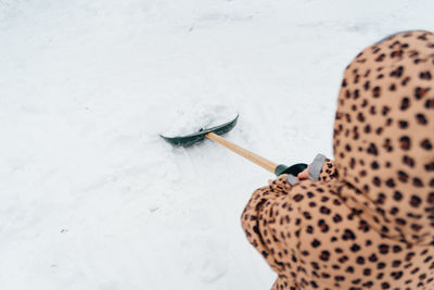 Low angle view of the little kid girl helping to clean pathway from snow with shovel