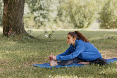 Woman stretching on exercise mat at park