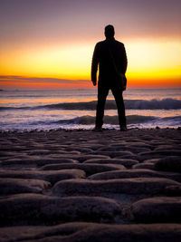 Full length of silhouette man standing at beach during sunset