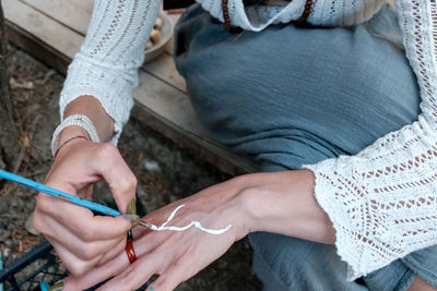 Low section of woman painting her hand