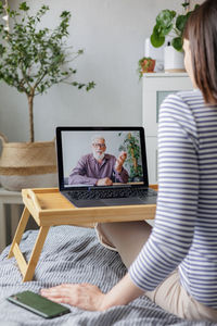 Midsection of woman using laptop at home