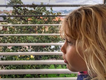 Side view of girl by window at home