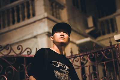 Low angle view of man standing against building at night