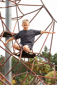 Low angle view of boy sitting on rope