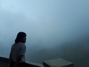 Woman looking at mountain during foggy weather