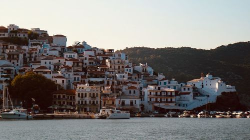 Buildings by sea against clear sky