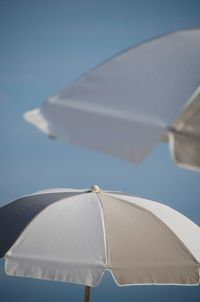Close-up of white umbrella against clear blue sky