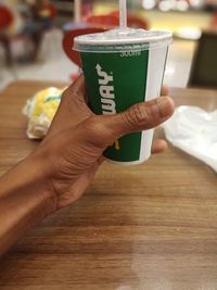 Midsection of person holding coffee cup on table