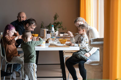 Multi generation family eating meal around kitchen table