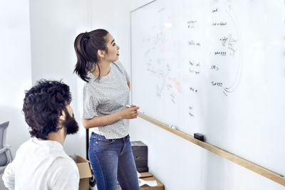 Business people examining data on whiteboard in creative office