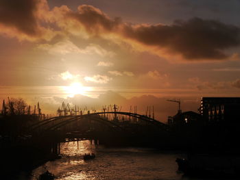 Silhouette bridge over river against sky during sunset