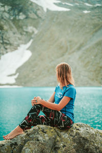 Woman sitting on rock looking at sea