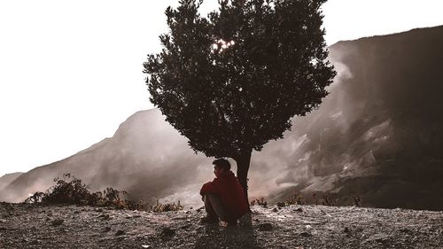 Man standing by tree against sky