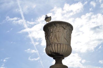 Low angle view of seagull perching on street light against sky