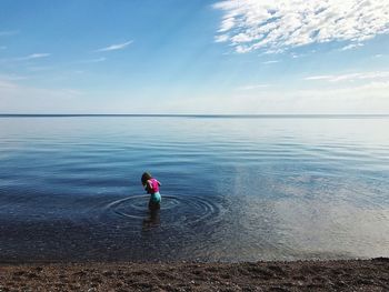 Rear view of girl on sea against sky