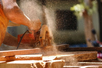 Cropped hand of carpenter cutting wood